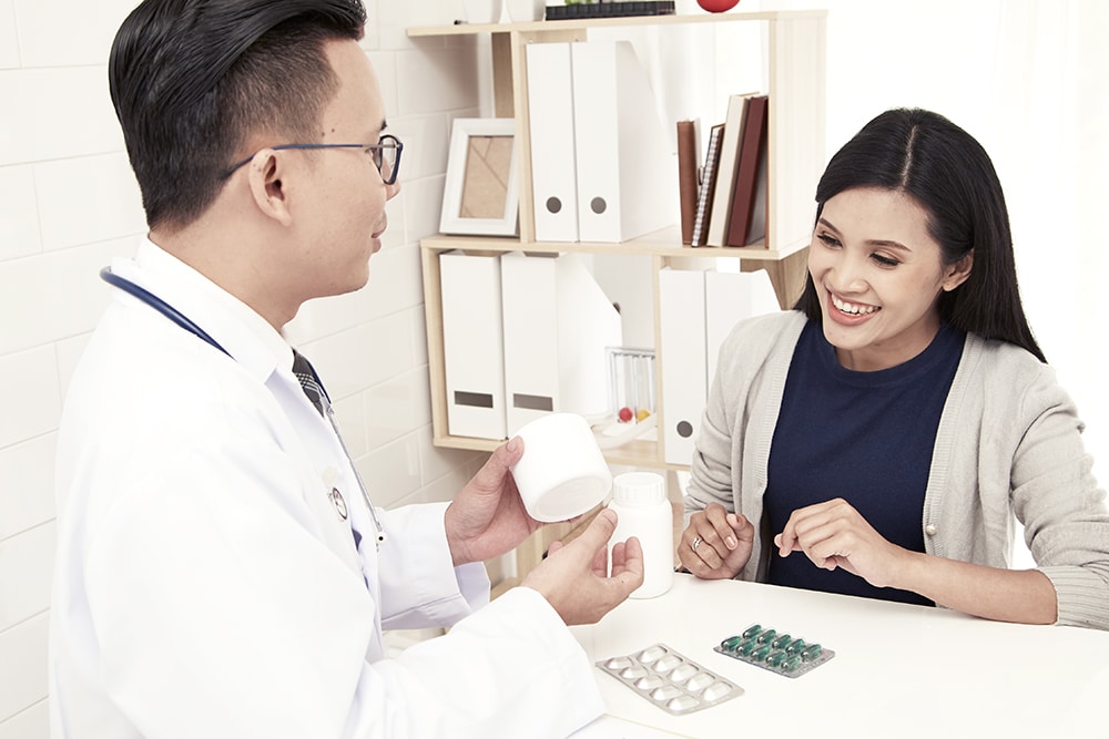 A young mother is talking to a doctor in his doctor's office. he is dressed in a white medical gown, Family planning concept